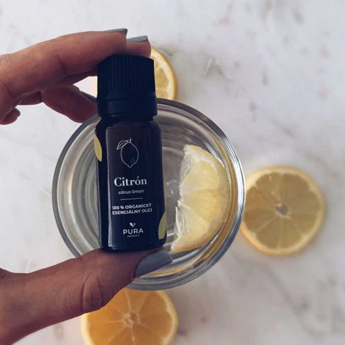 Citrónový esenciálny olej fľaša s pohárom a kúskami citrónu